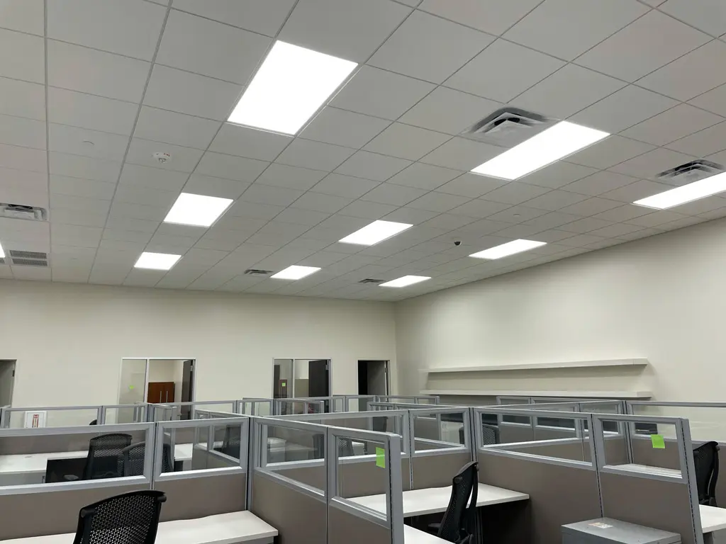 Empty office space with cubicles and lights.