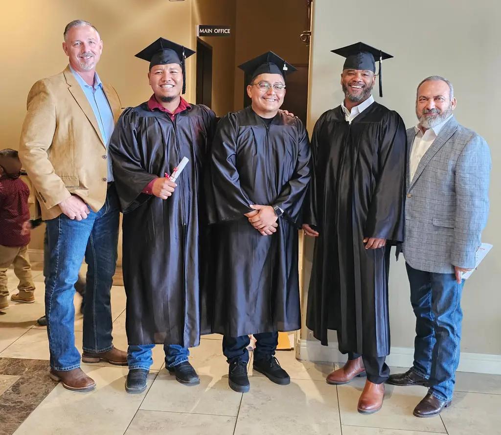 Graduates in caps and gowns with supporters.