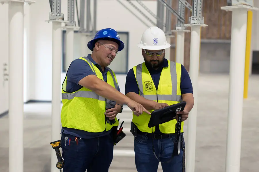 Two workers reviewing data on a tablet.