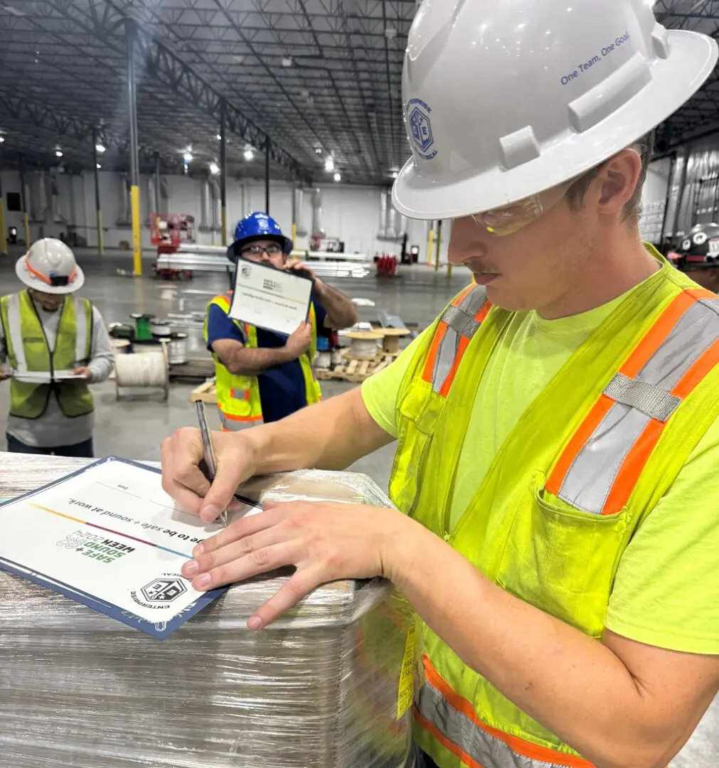 Workers in safety gear handling paperwork.