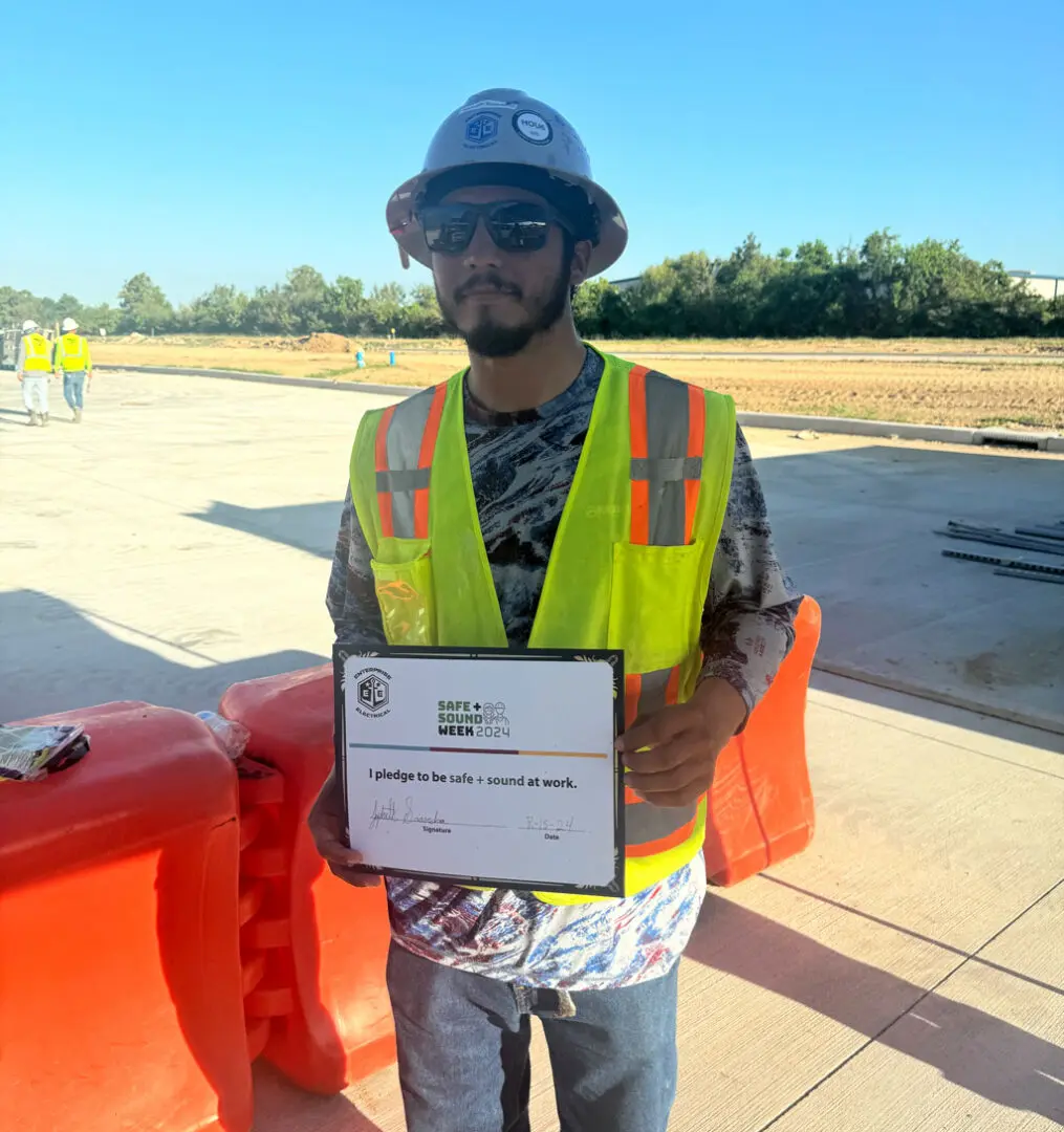 Construction worker holding safety pledge sign.