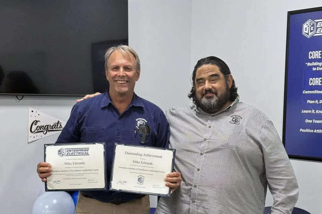 Two men holding certificates in celebration.