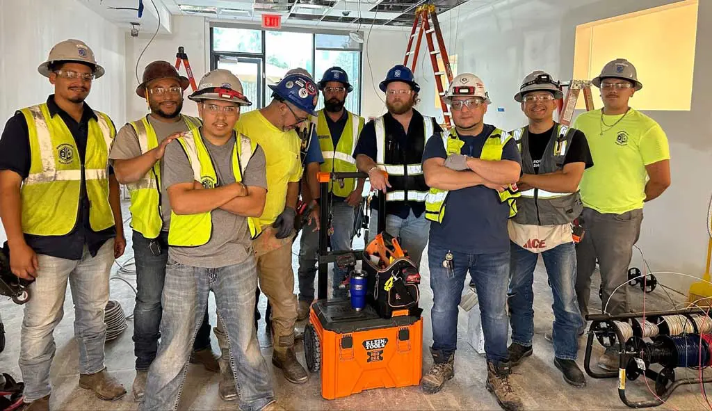 Construction team posing with equipment and tools.
