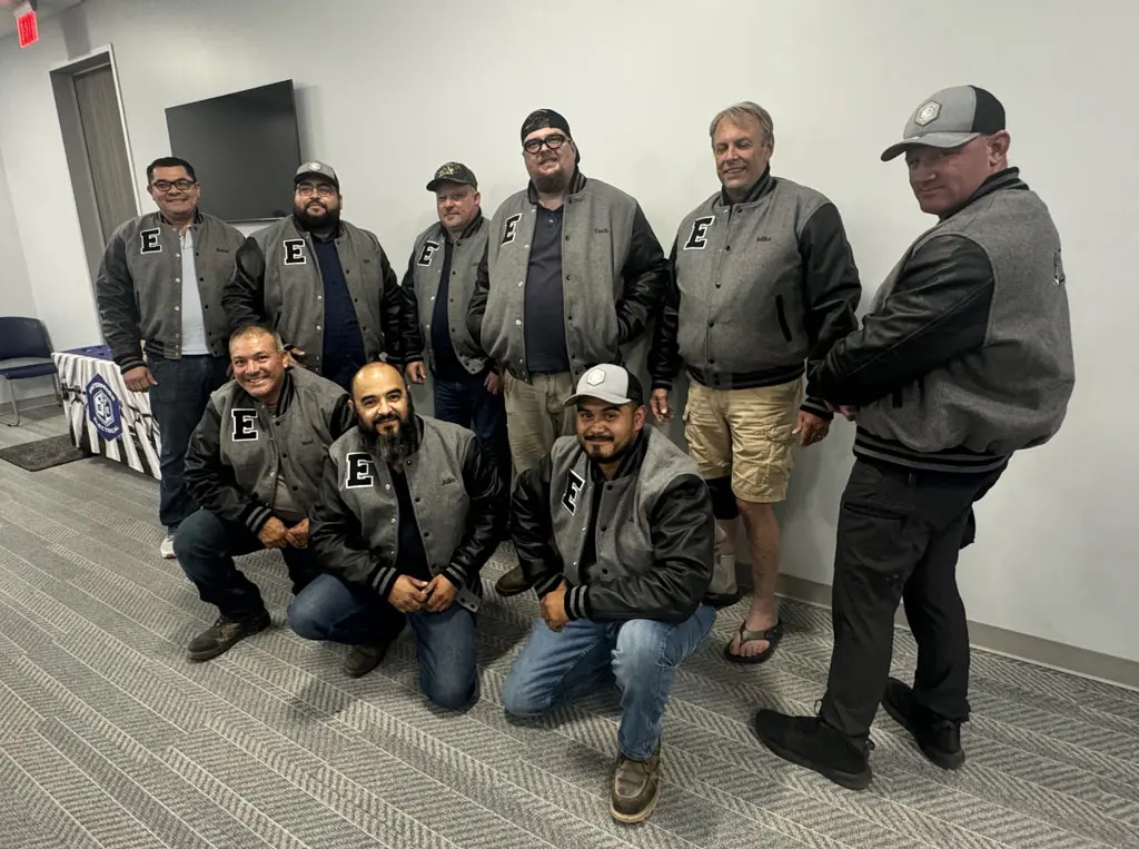 Group of men in matching jackets posing together.